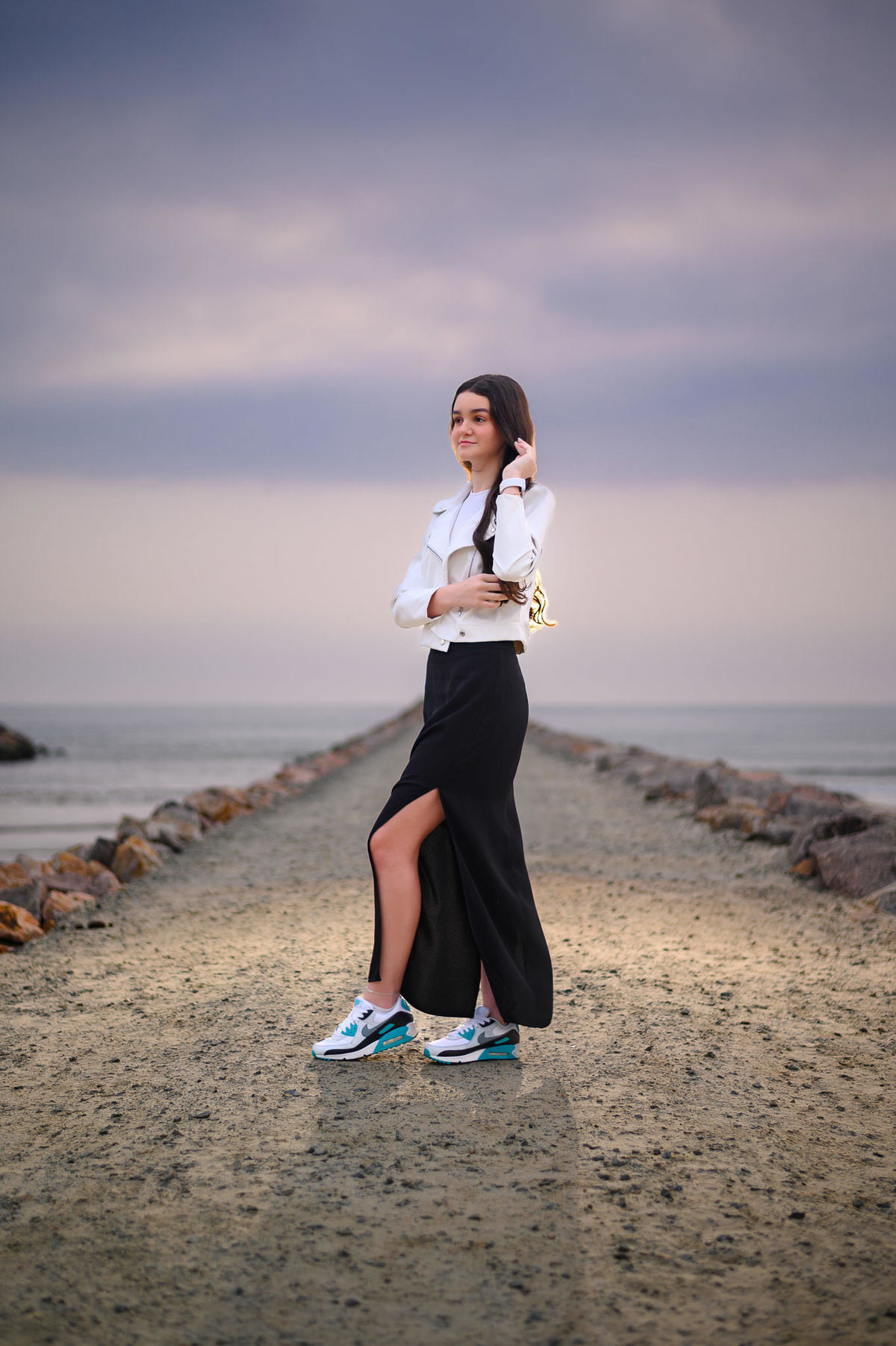 Ensaio de 15 anos em Itapema SC no molhe, debutante em pé com o mar ao fundo em manhã nublada