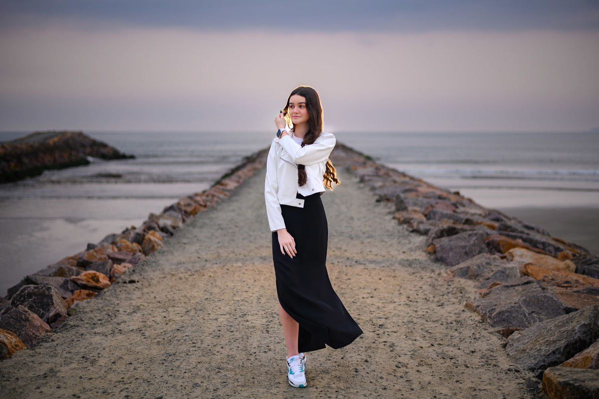 Ensaio de 15 anos em Itapema SC no molhe, debutante em pé com o mar ao fundo em manhã nublada