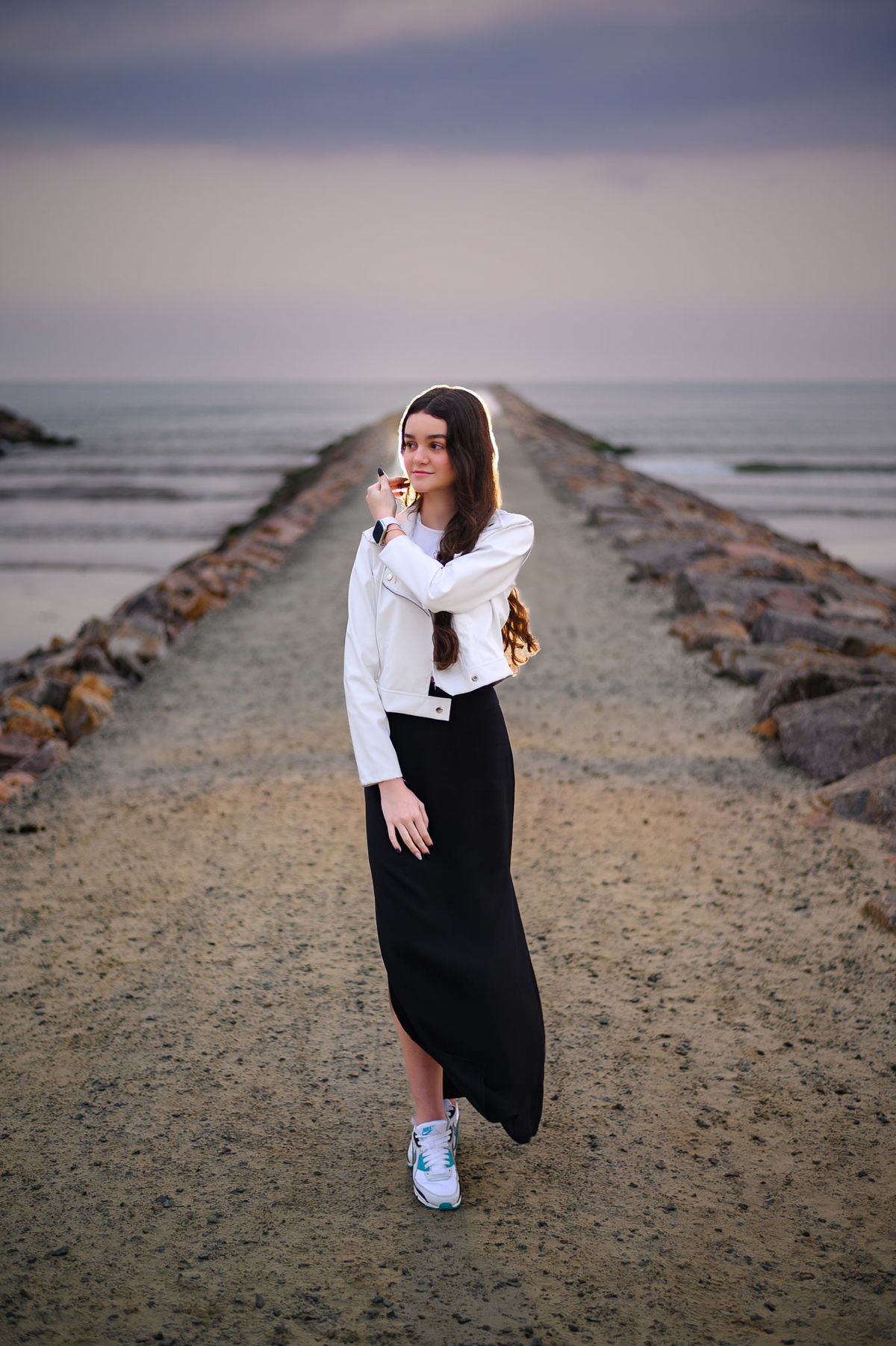 Ensaio de 15 anos em Itapema SC no molhe, debutante em pé com o mar ao fundo em manhã nublada