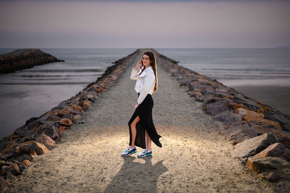 Ensaio de 15 anos em Itapema SC no molhe, debutante em pé com o mar ao fundo em manhã nublada