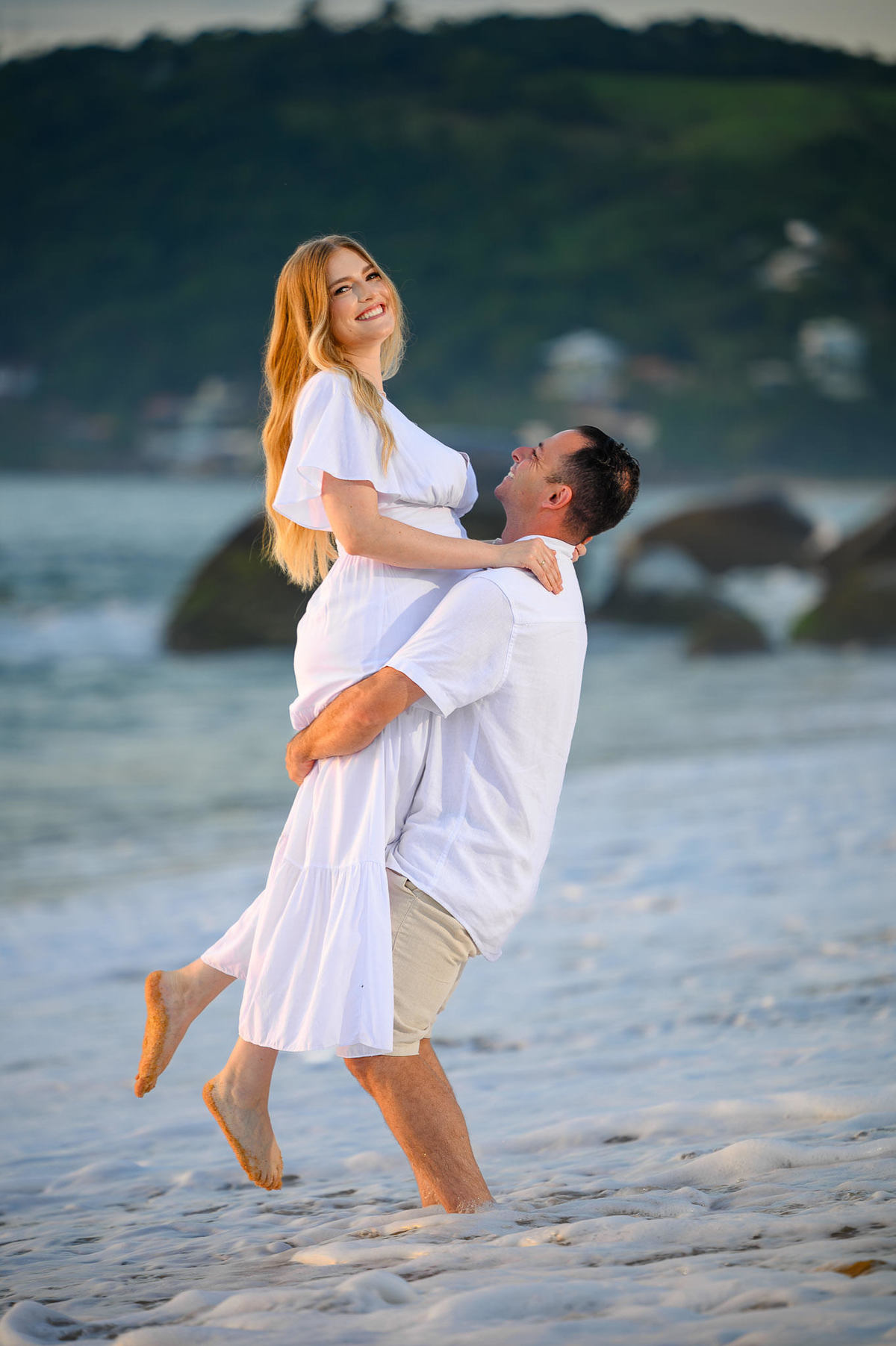 casal feliz em ensaio pré wedding na praia de Balneário Camboriú SC ao amanhecer posando para fotógrafo profissional