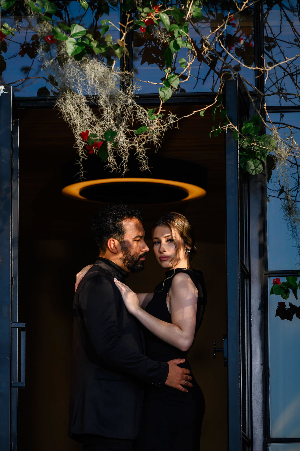 Casal em ensaio pré-wedding elegante na Casa do Maciço em Florianópolis, posando sob lustre decorativo em ambiente interno sofisticado