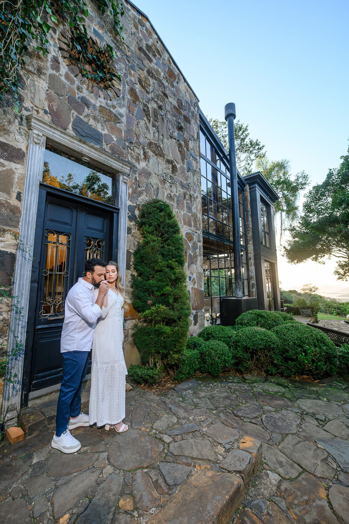 Casal em ensaio pré-wedding na Casa do Maciço, Florianópolis, enquadramento aberto valorizando arquitetura do local