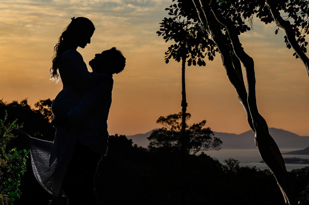 Silhueta de Madally e Stefley em pré-wedding na Casa Maciço com Florianópolis ao fundo