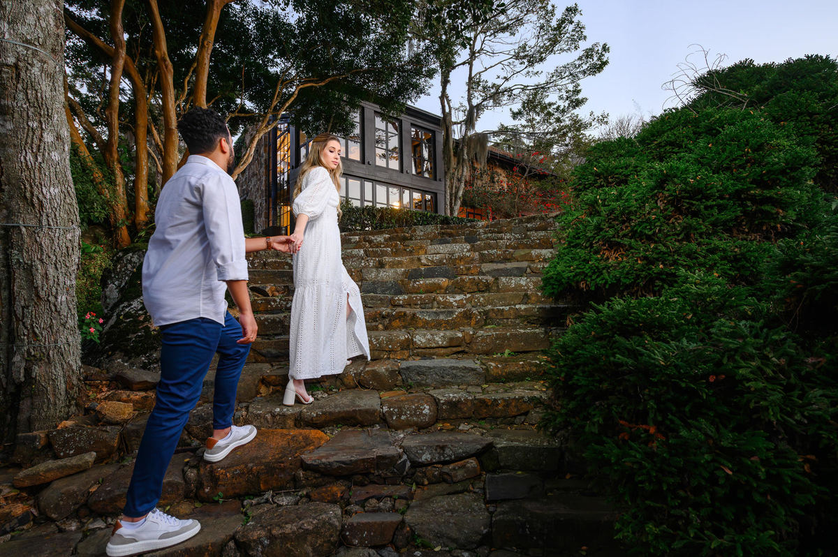 Casal em ensaio pré-wedding na Casa do Maciço, Florianópolis, pose intimista em escadaria com cenário natural ao fundo