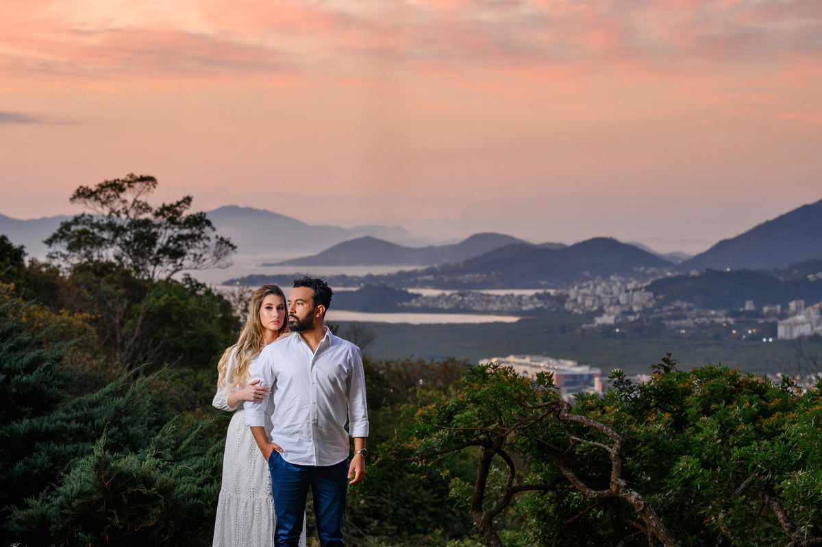 Casal em ensaio pré-wedding com vista panorâmica de Florianópolis ao fundo, realizado na Casa do Maciço