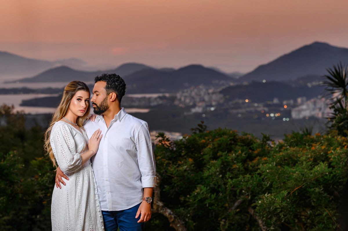 Ensaio pré-wedding em Florianópolis com casal em primeiro plano e cidade ao fundo ao entardecer