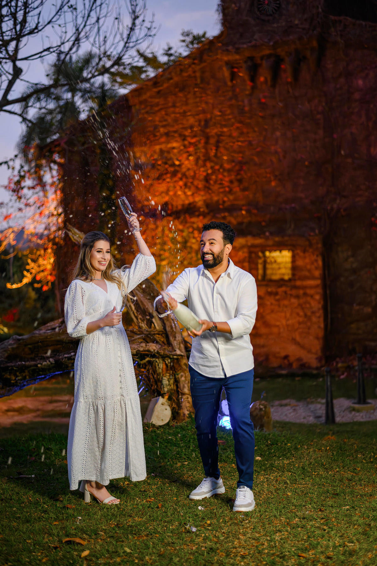 Ensaio pré-wedding em Florianópolis, SC – casal brindando com taças em cenário rústico iluminado à noite