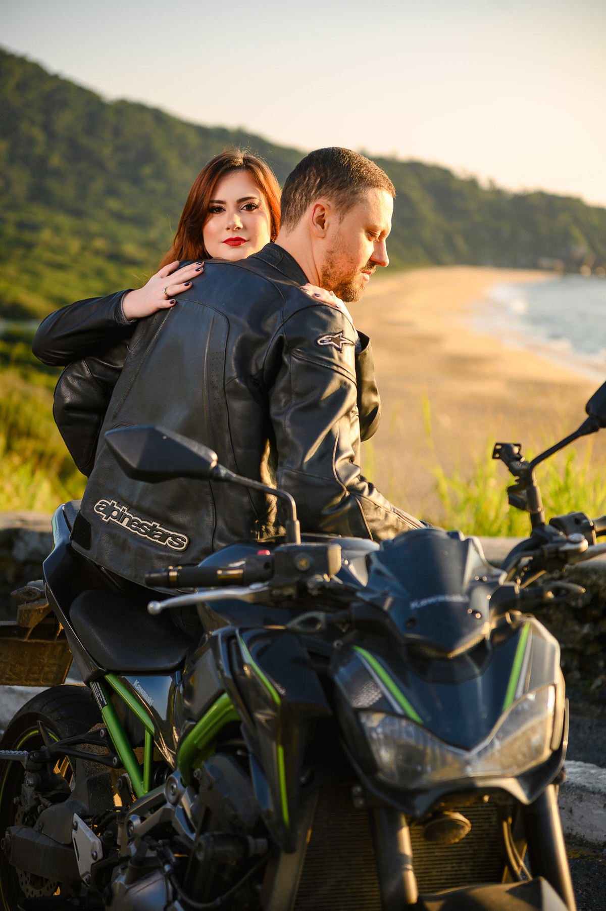 Casal em ensaio pré casamento ao lado de moto com vista para a praia em Santa Catarina