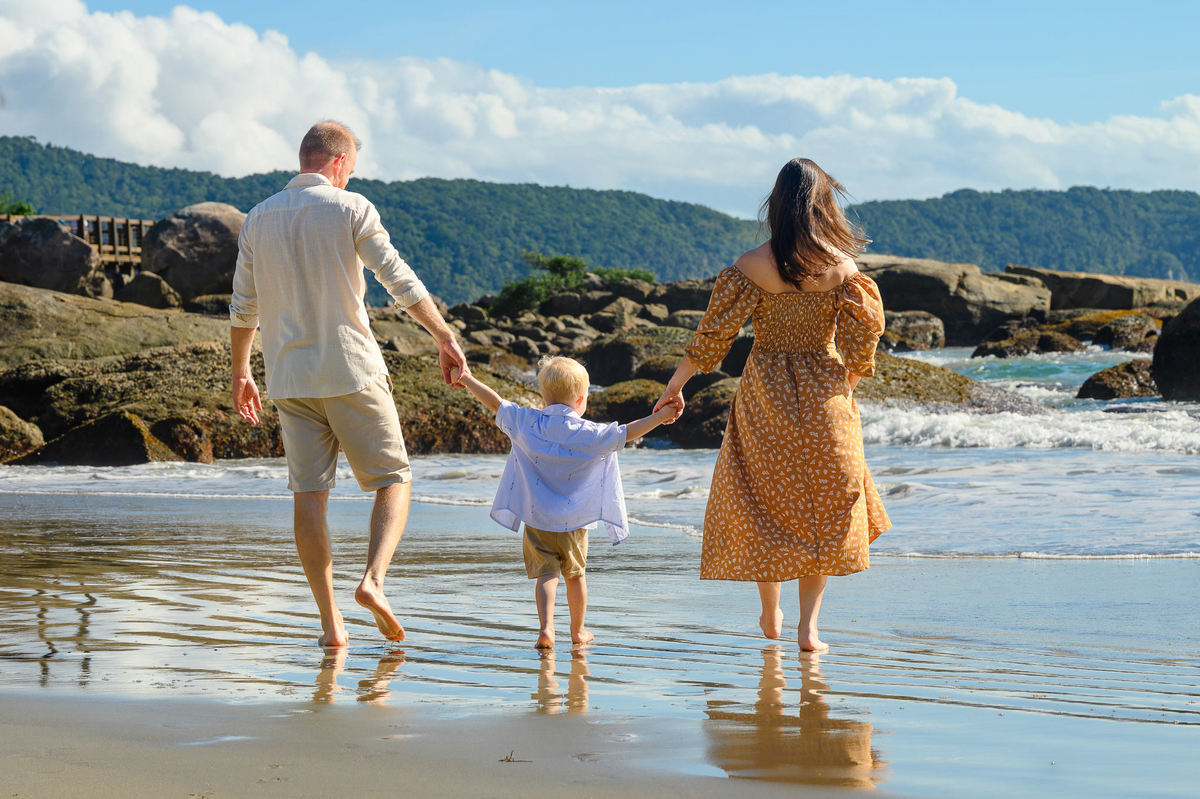 Família caminhando na praia durante ensaio gestante em Bombinhas SC