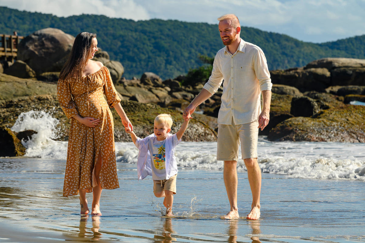 Família caminhando na praia durante ensaio gestante em Bombinhas SC