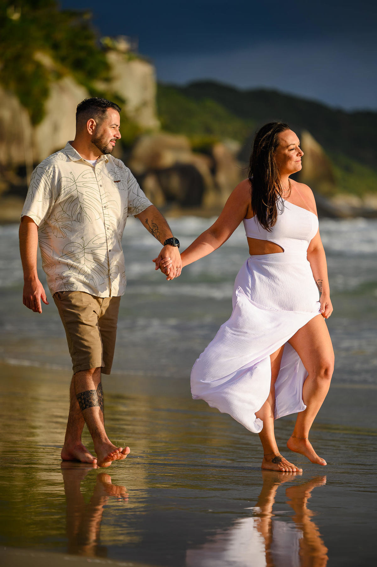 Ensaio de casal caminhando de mãos dadas na beira do mar em Bombinhas SC, fotografia de casal na praia