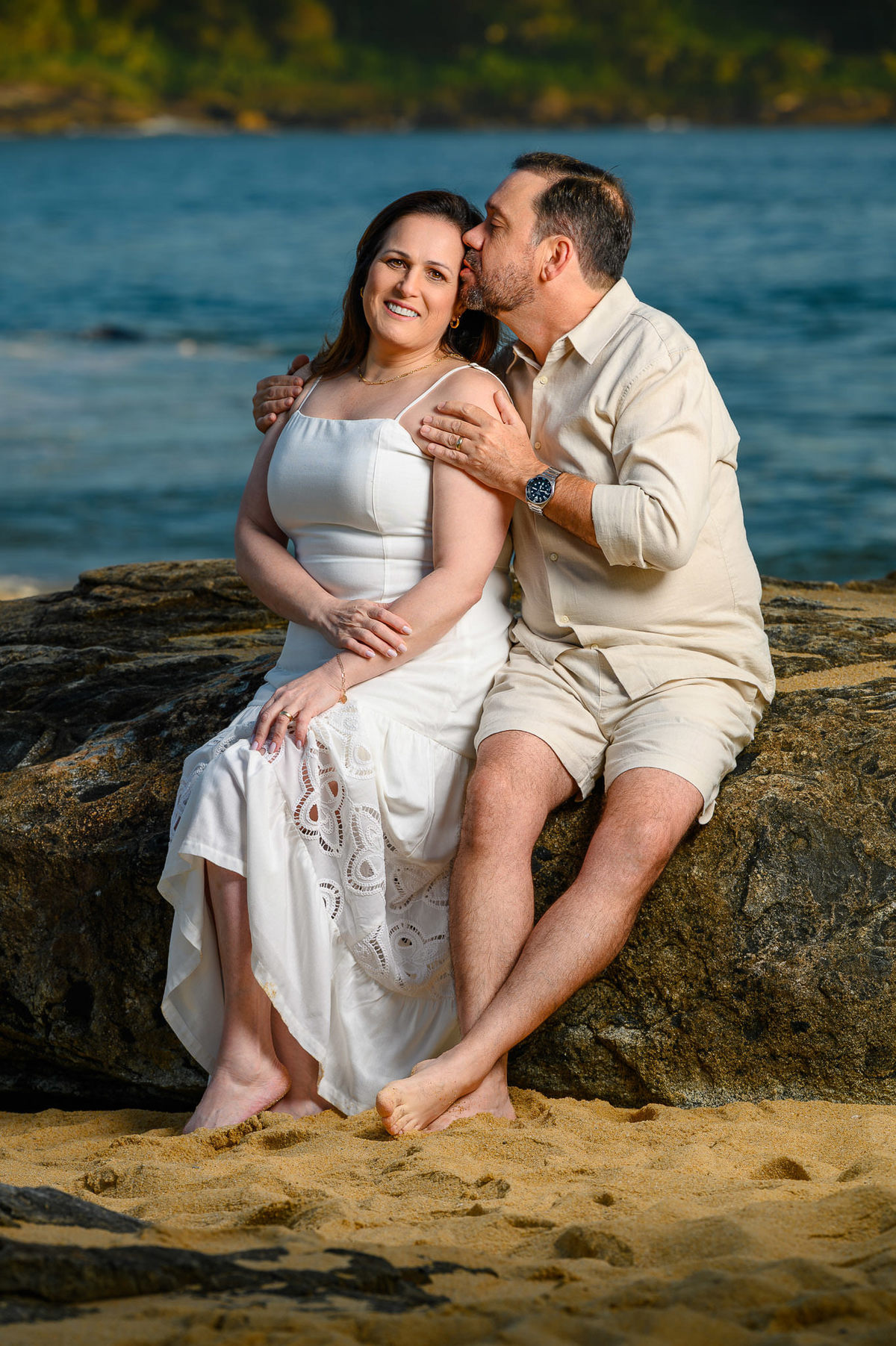 Casal sentado nas pedras durante ensaio de família na Praia do Estaleirinho em Balneário Camboriú