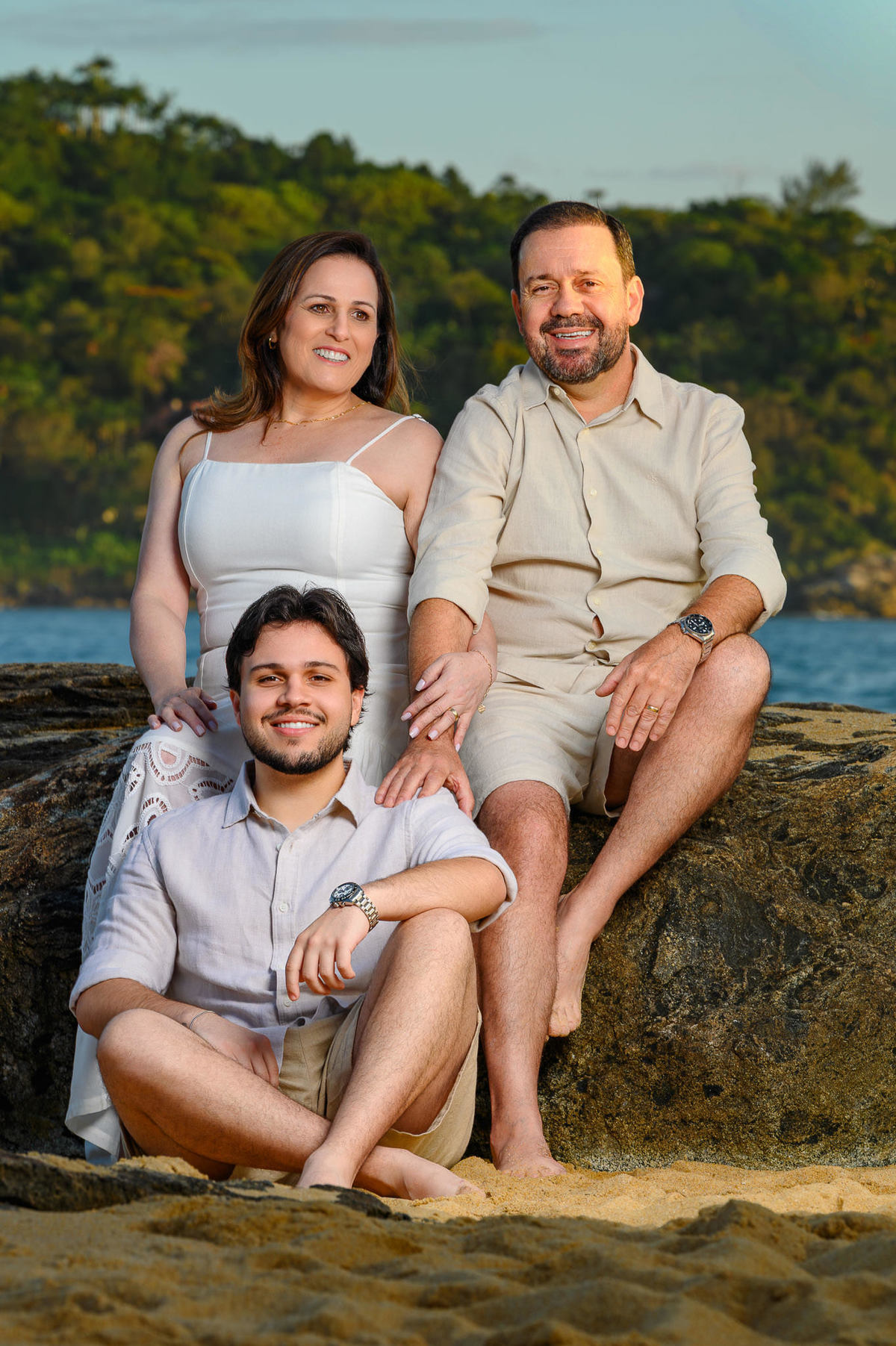 Família sentada sobre as pedras com o mar ao fundo em Balneário Camboriú Santa Catarina