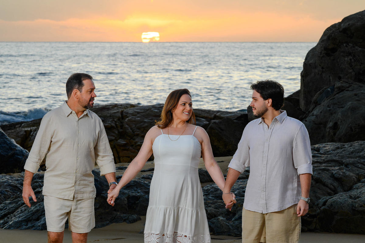 Família caminhando de mãos dadas na Praia do Estaleirinho ao amanhecer em Balneário Camboriú SC