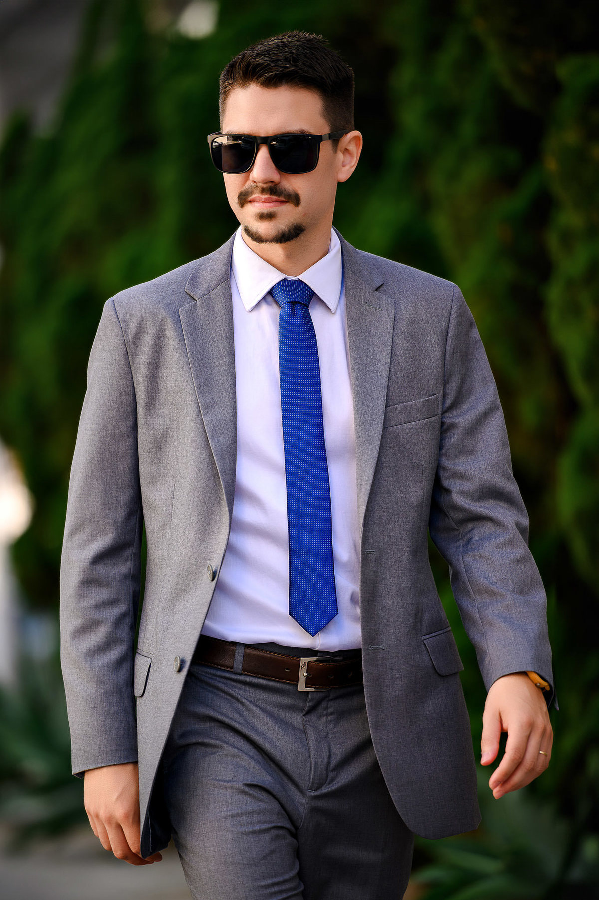 Retrato corporativo profissional de advogado caminhando em ambiente externo com vegetação ao fundo, fotografia de posicionamento profissional em Balneário Camboriú.