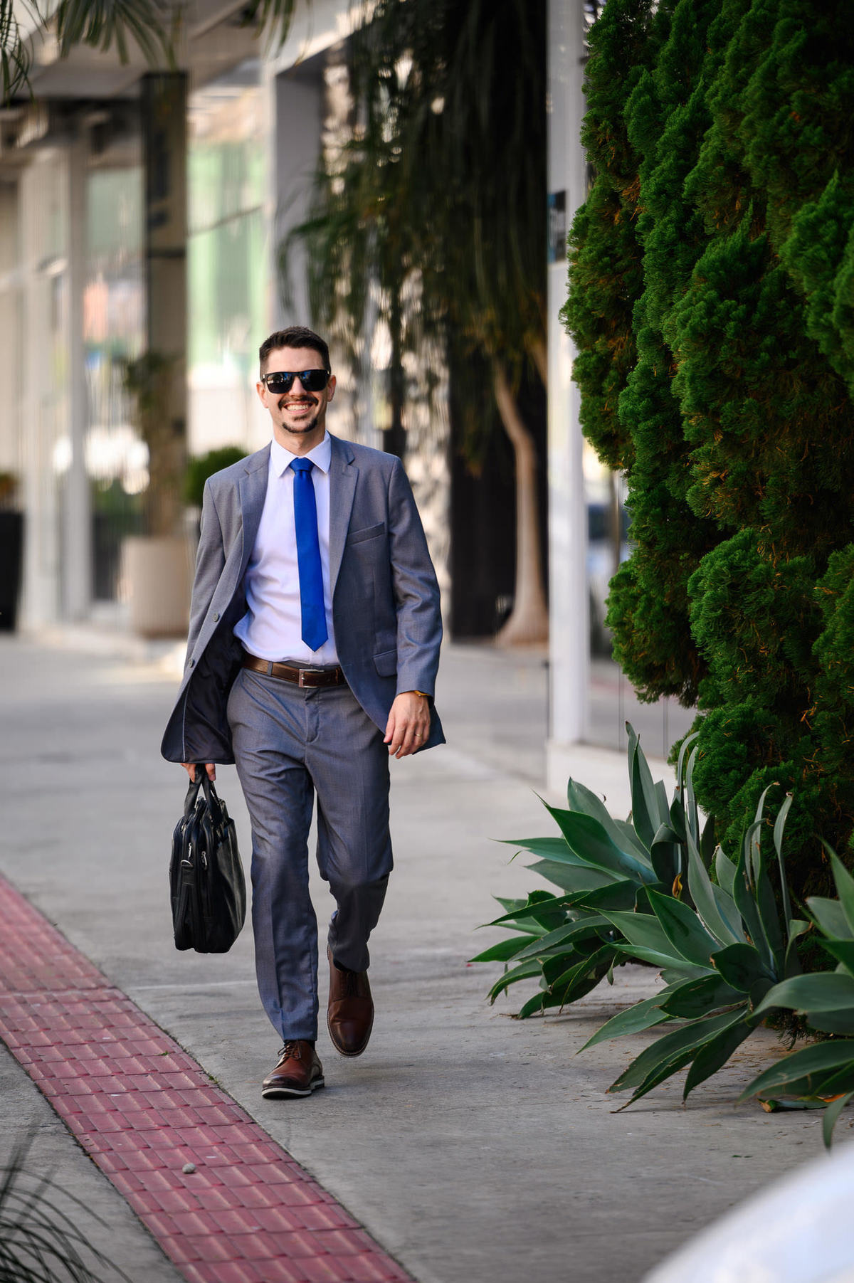 Retrato corporativo profissional de advogado caminhando em ambiente externo com vegetação ao fundo, fotografia de posicionamento profissional em Balneário Camboriú.