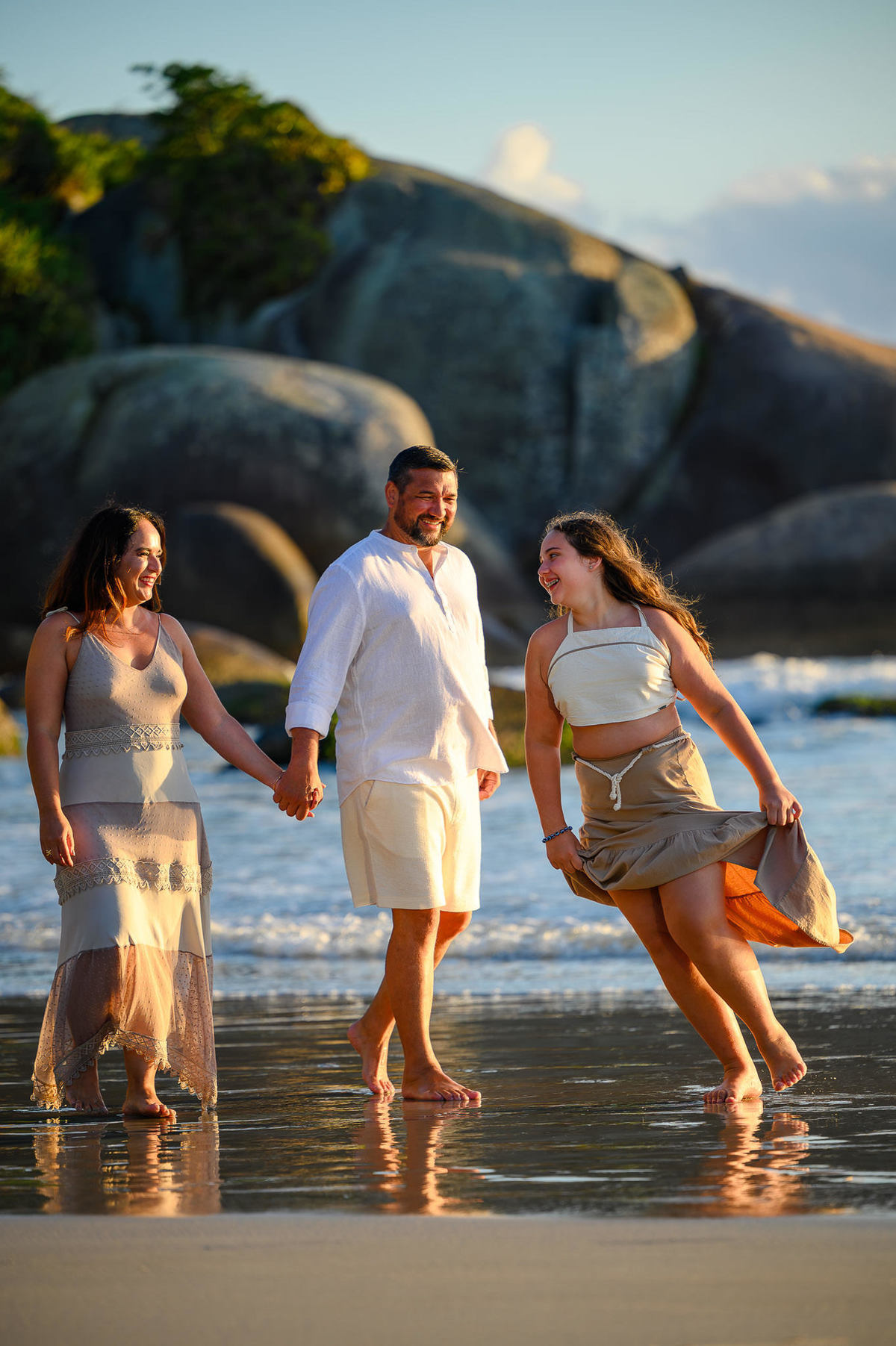 Família caminhando na areia durante ensaio fotográfico em Bombinhas