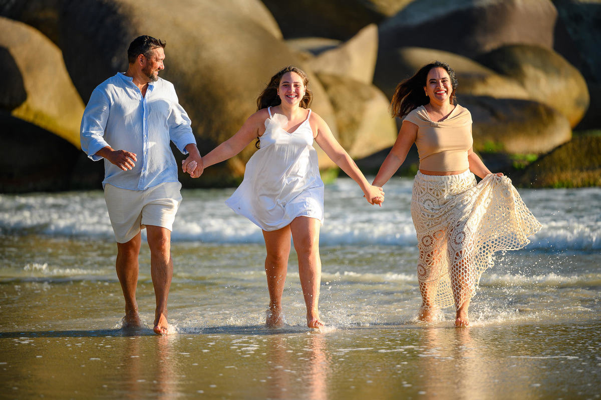 Família caminhando na areia durante ensaio fotográfico em Bombinhas