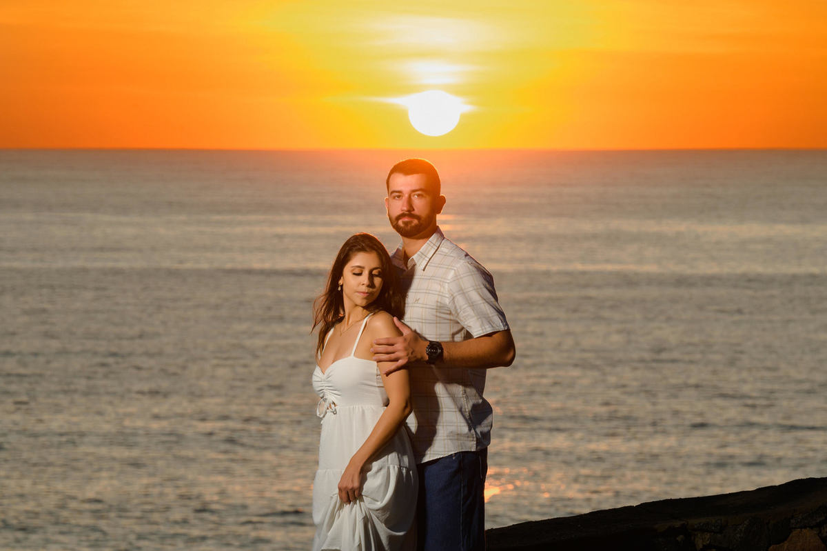 Casal abraçado com o mar ao fundo e luz suave do amanhecer na Praia de Taquarinhas, Balneário Camboriú, durante ensaio pré-wedding