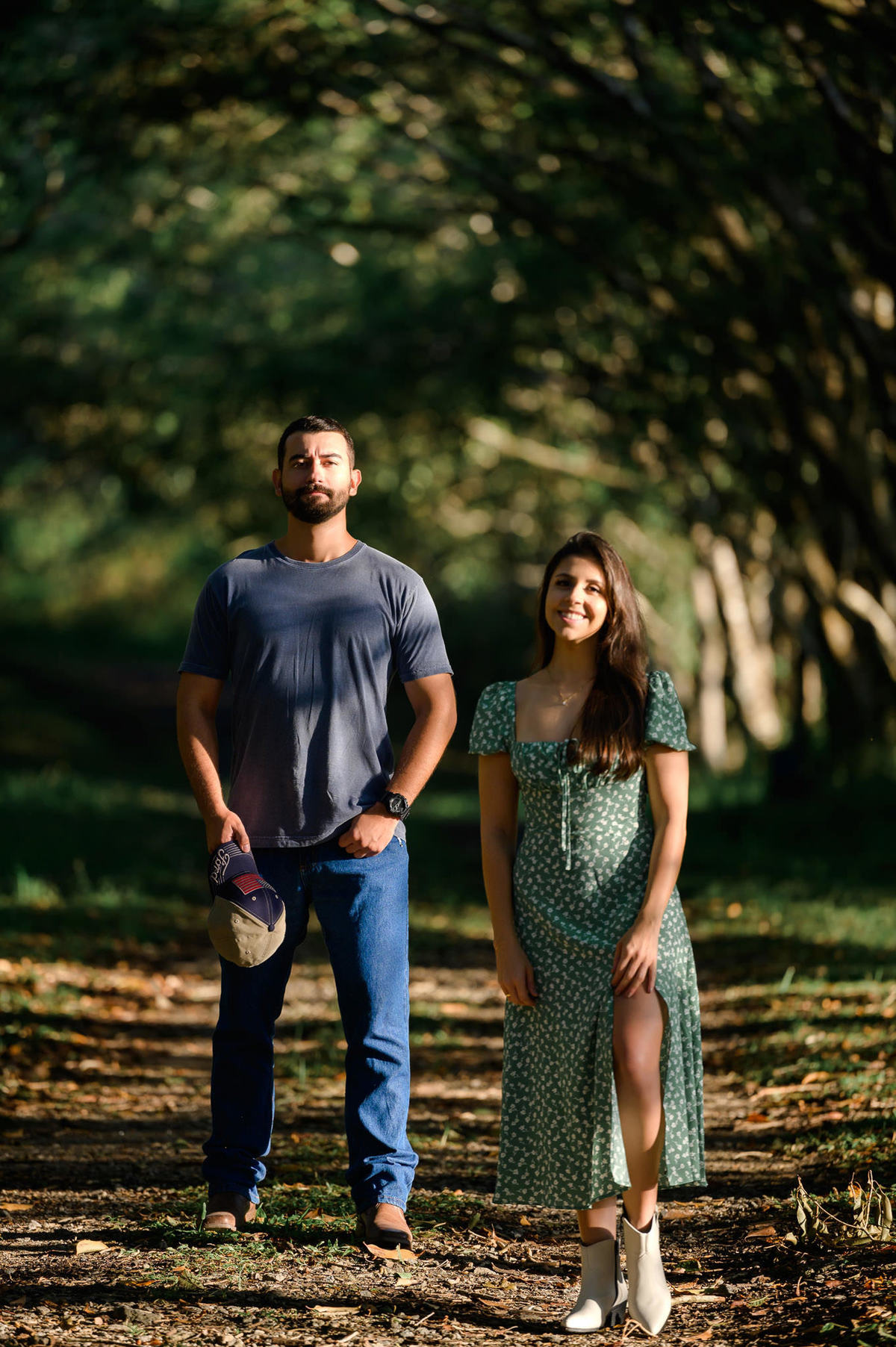 Casal caminhando lado a lado em estrada cercada por árvores no bosque de Taquarinhas, Balneário Camboriú, em ensaio pré-wedding