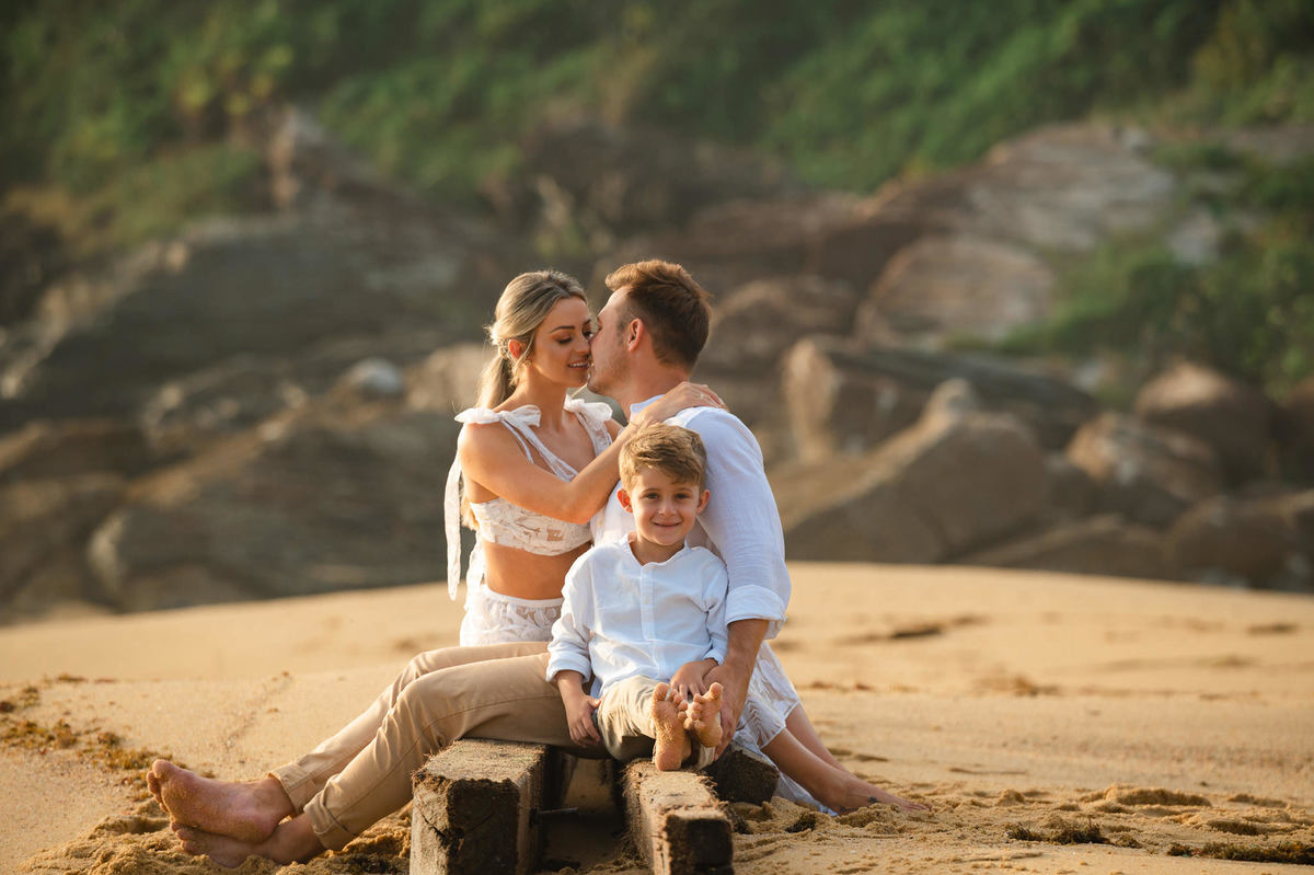 Família sorrindo durante ensaio pré-wedding ao amanhecer na praia em Itapema SC, com céu claro da manhã e clima leve.