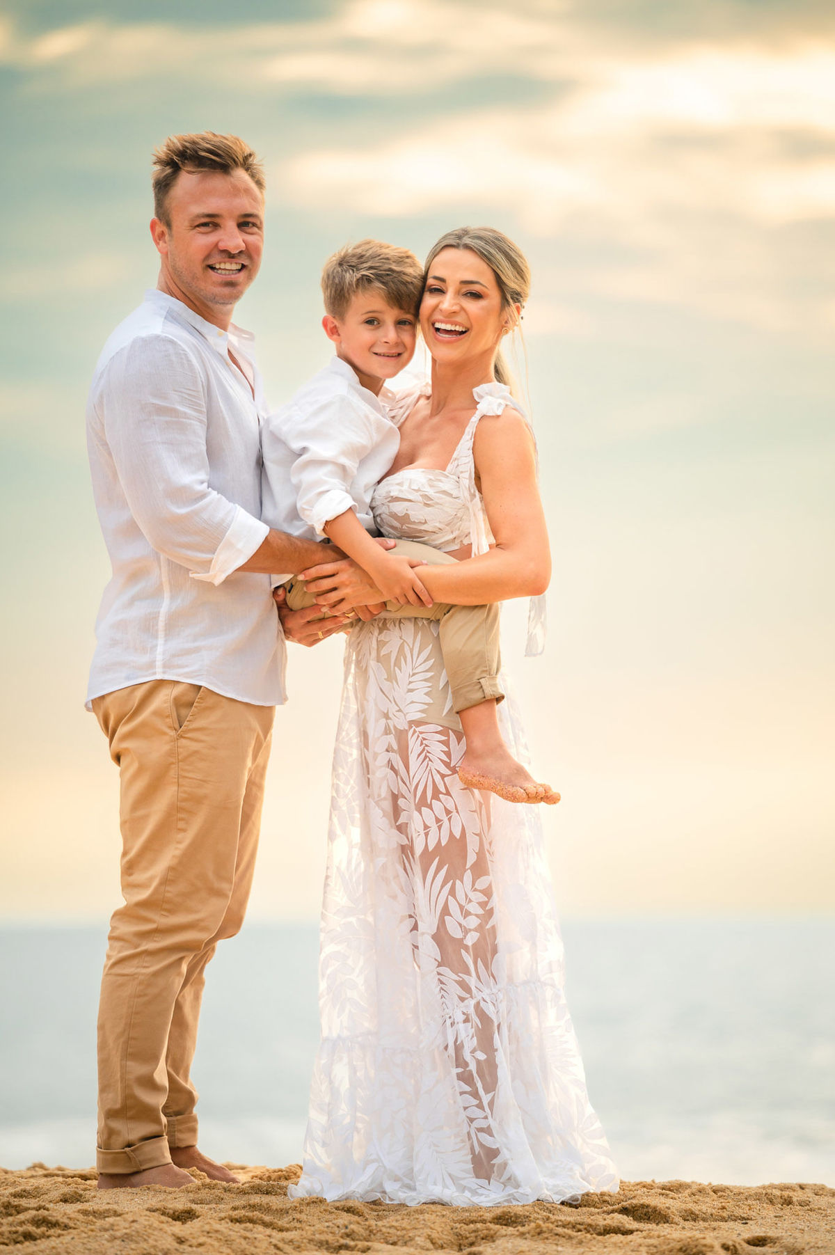 Fotografia de ensaio pré-casamento em família ao amanhecer na praia de Itapema SC, com casal e filho em momento espontâneo.