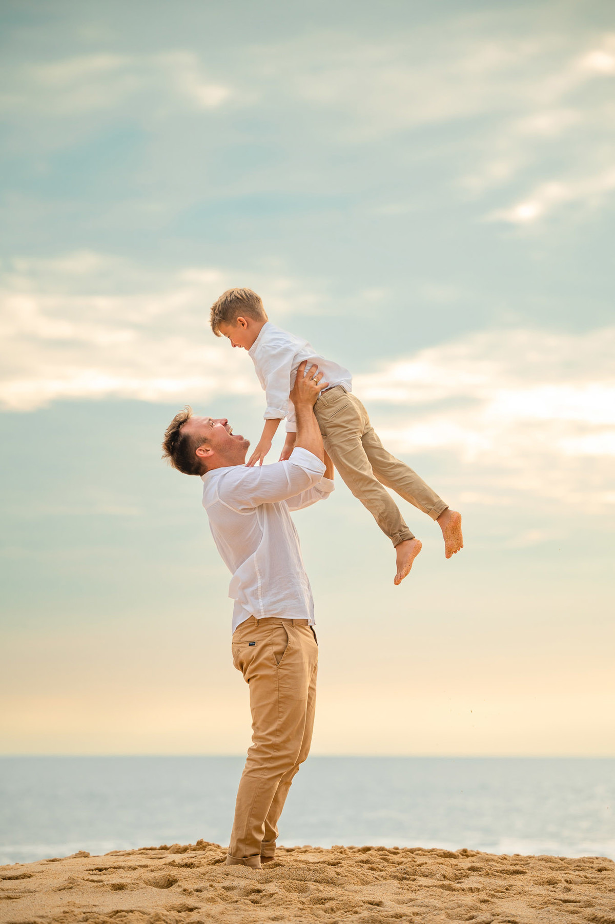 Casal com o filho em ensaio pré-casamento ao amanhecer na praia de Itapema SC, segurando as mãos e brincando na areia.