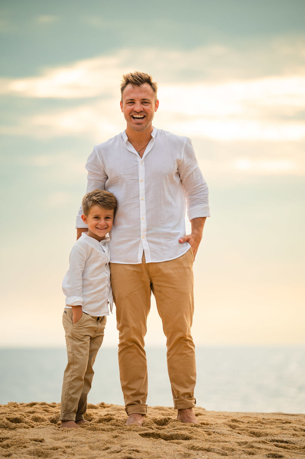 Casal com o filho em ensaio pré-casamento ao amanhecer na praia de Itapema SC, segurando as mãos e brincando na areia.