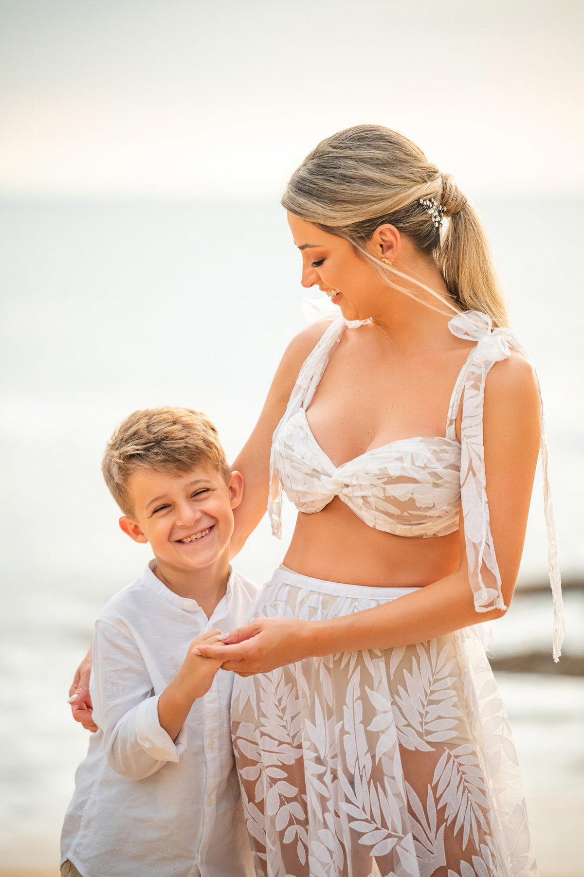 Casal com o filho em ensaio pré-casamento ao amanhecer na praia de Itapema SC, segurando as mãos e brincando na areia.