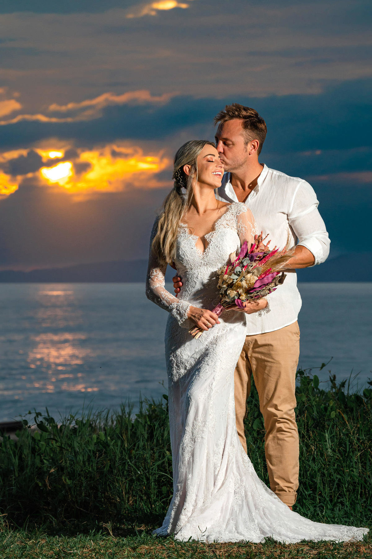 Casal em ensaio pré-wedding ao amanhecer na praia em Itapema SC, em meio à natureza, com luz suave da manhã e mar ao fundo.