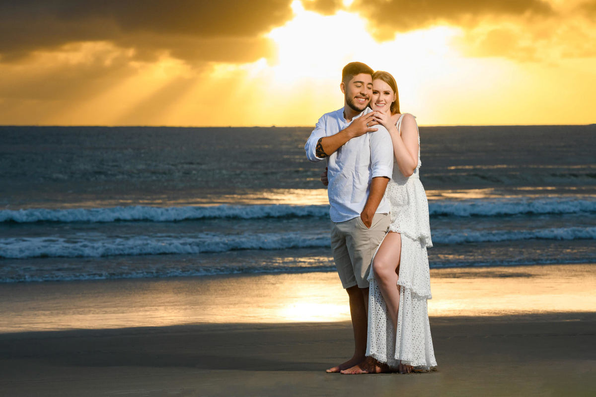 Close do casal se abraçando na beira da água durante ensaio pré-wedding ao amanhecer em Bombinhas, Santa Catarina