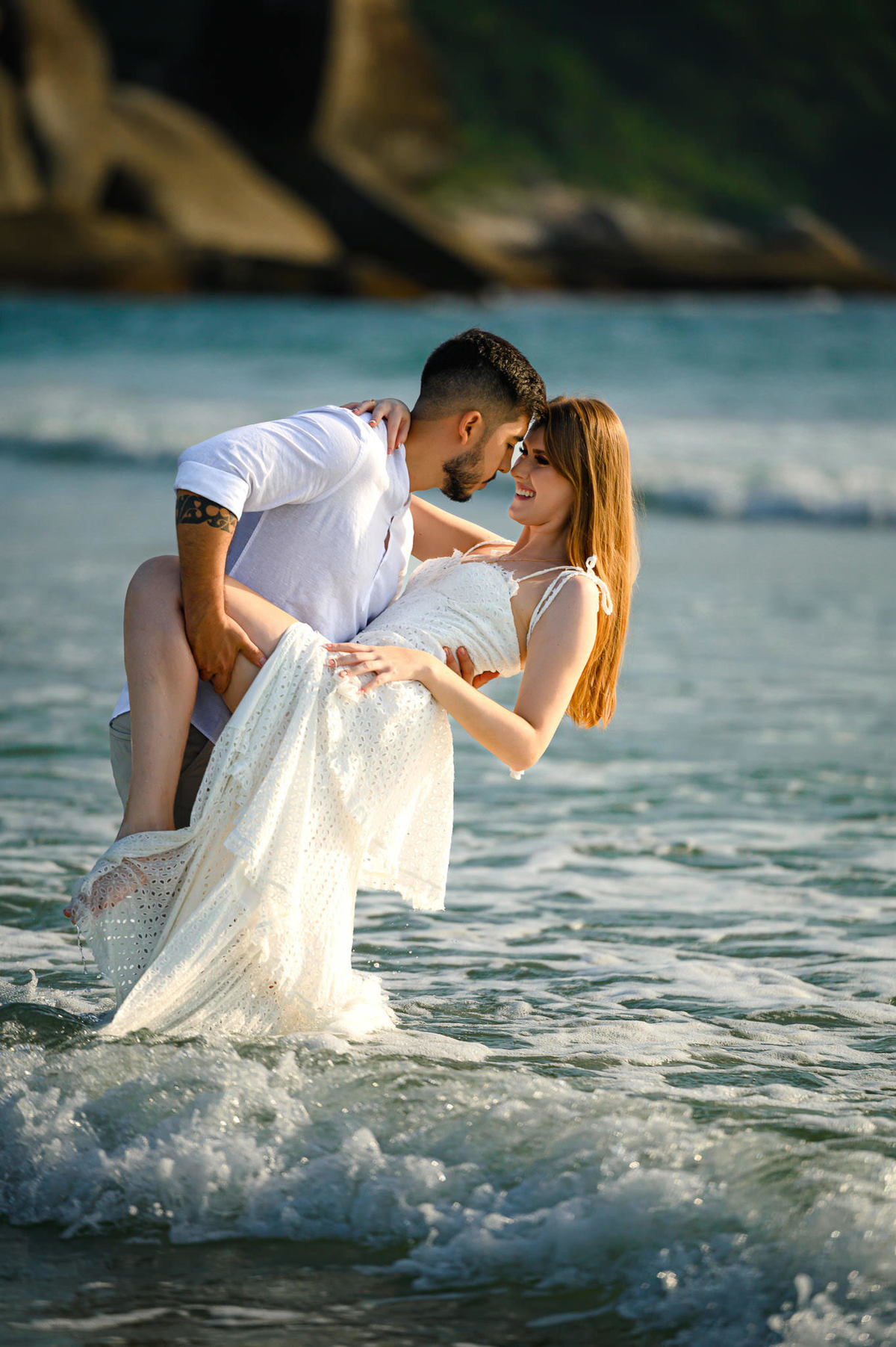 Casal se abraçando dentro do mar durante ensaio pré-wedding ao amanhecer na praia de Bombas em Bombinhas, SC