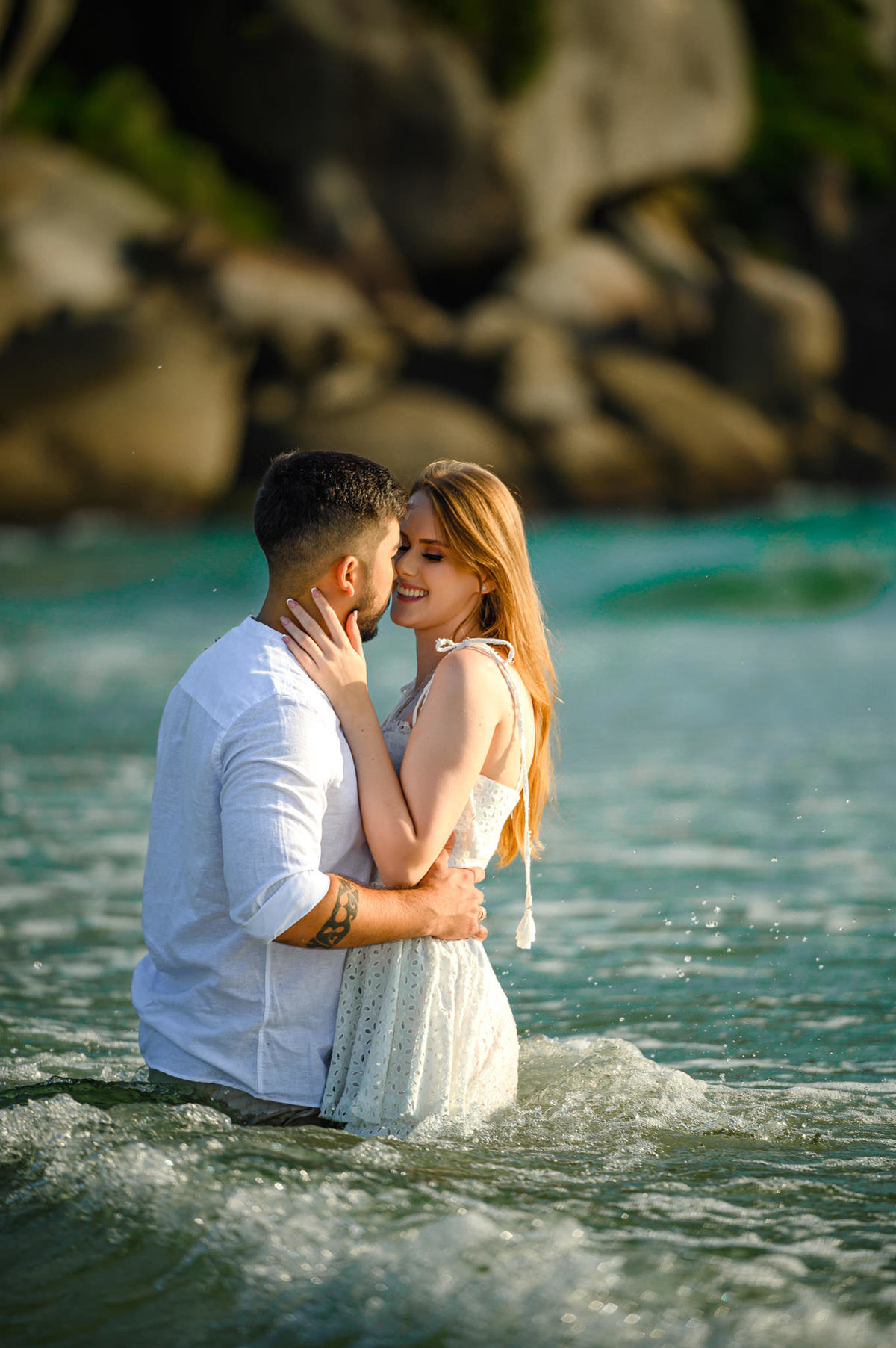 Casal se abraçando dentro do mar durante ensaio pré-wedding ao amanhecer na praia de Bombas em Bombinhas, SC