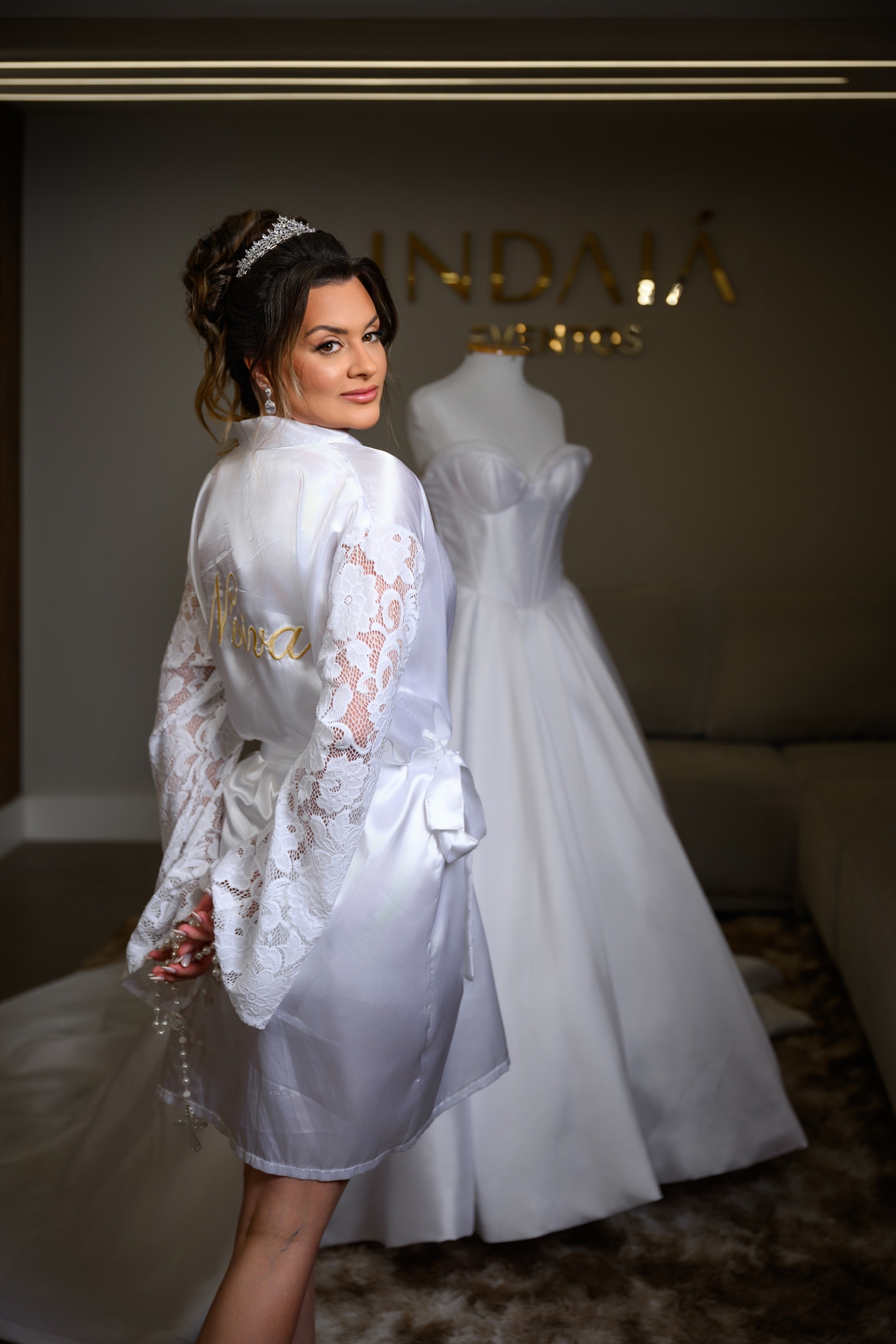 Noiva de robe com vestido ao fundo em espaço de making of organizado