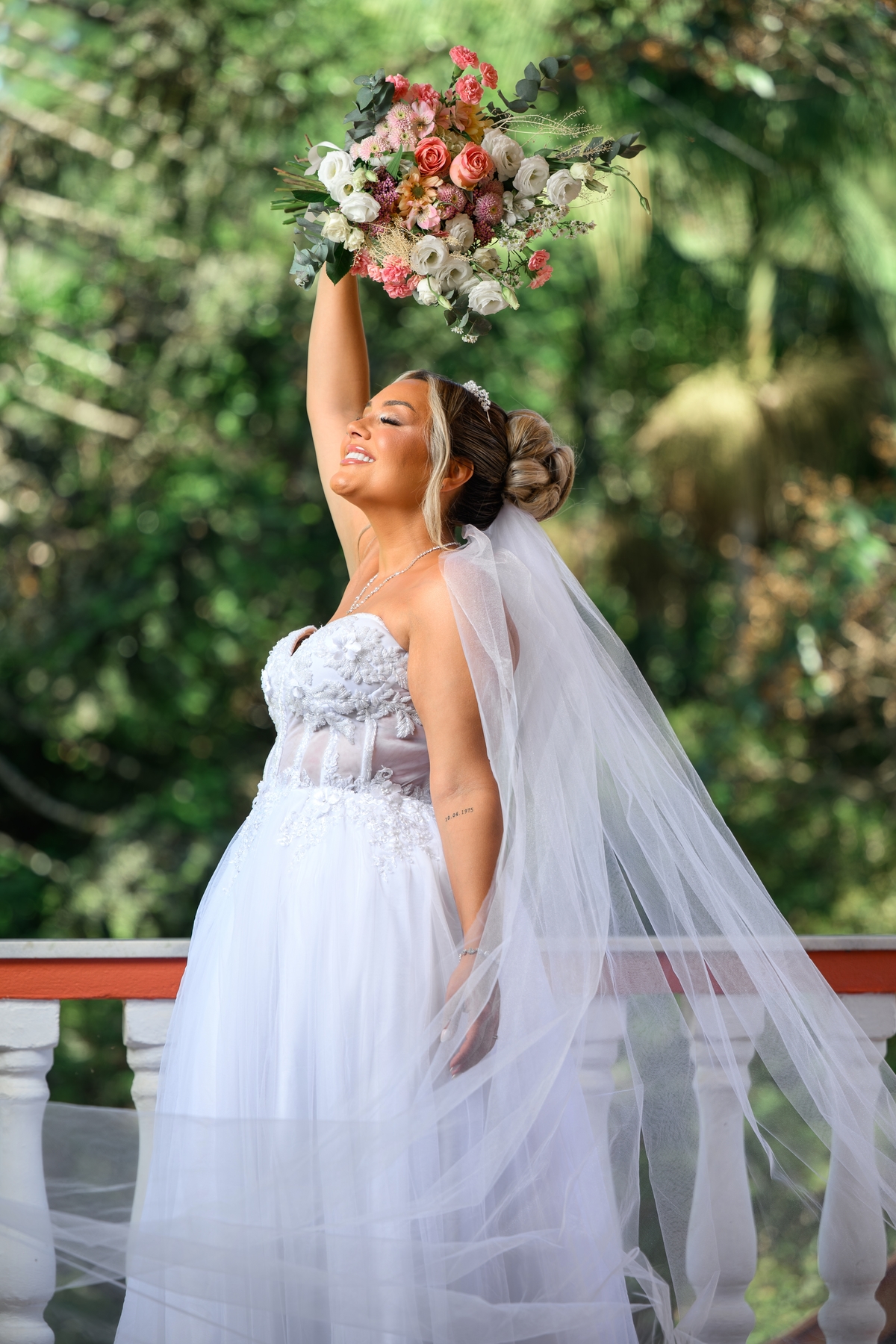 Noiva pronta levantando o buquê com véu e vestido