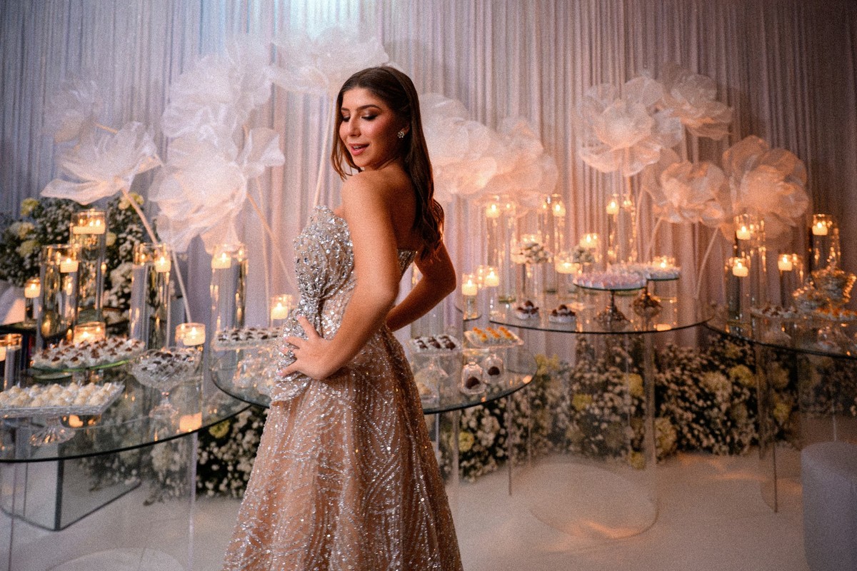 Debutante fotografada diante de uma decoração elaborada de festa de 15 anos.