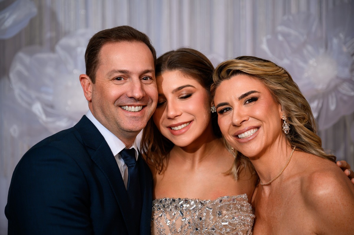 Debutante entre os pais em retrato de família durante a festa de 15 anos.