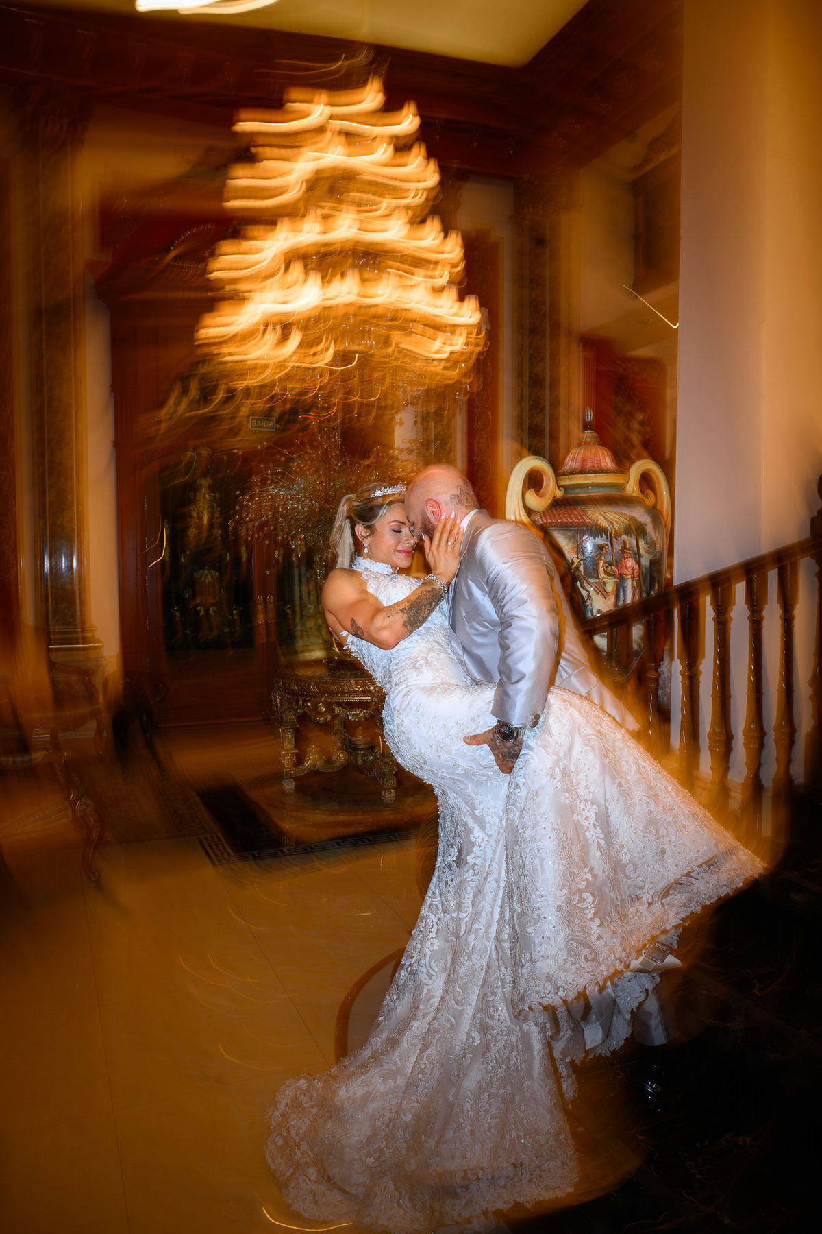 Fotografia editorial do beijo dos noivos sob o lustre do Palazzo Canello em Itajaí