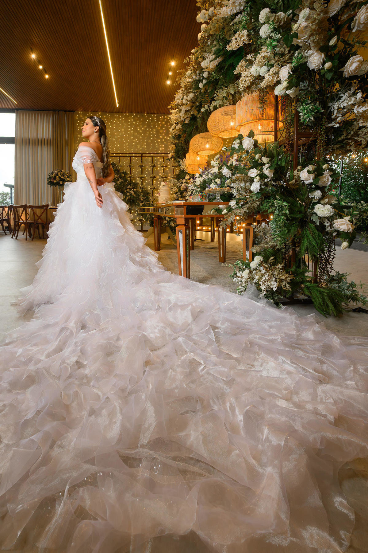 Noiva com longa cauda do vestido integrada à decoração floral do Indaiá Eventos.