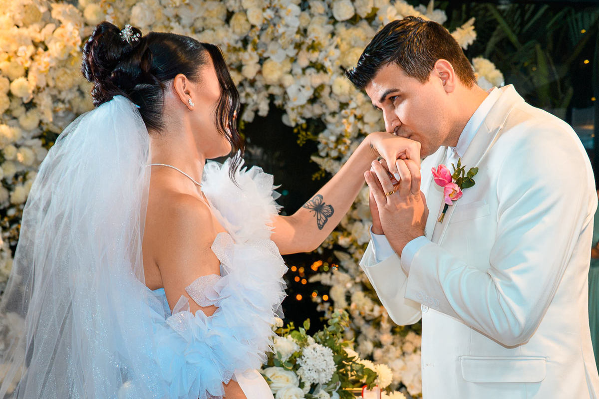  Noivo beijando a mão da noiva após a troca de alianças