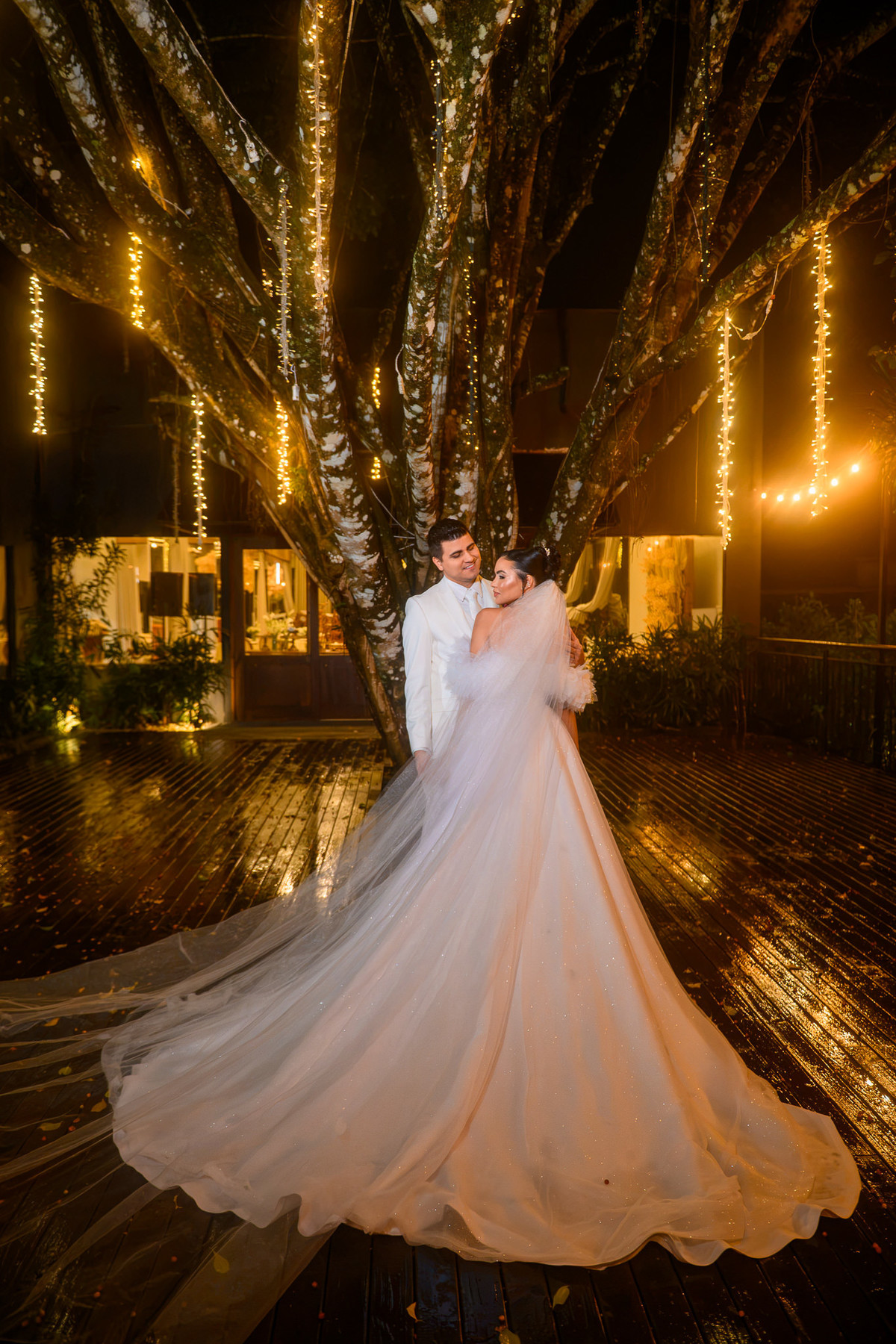  Casal posando junto sob iluminação quente no jardim

