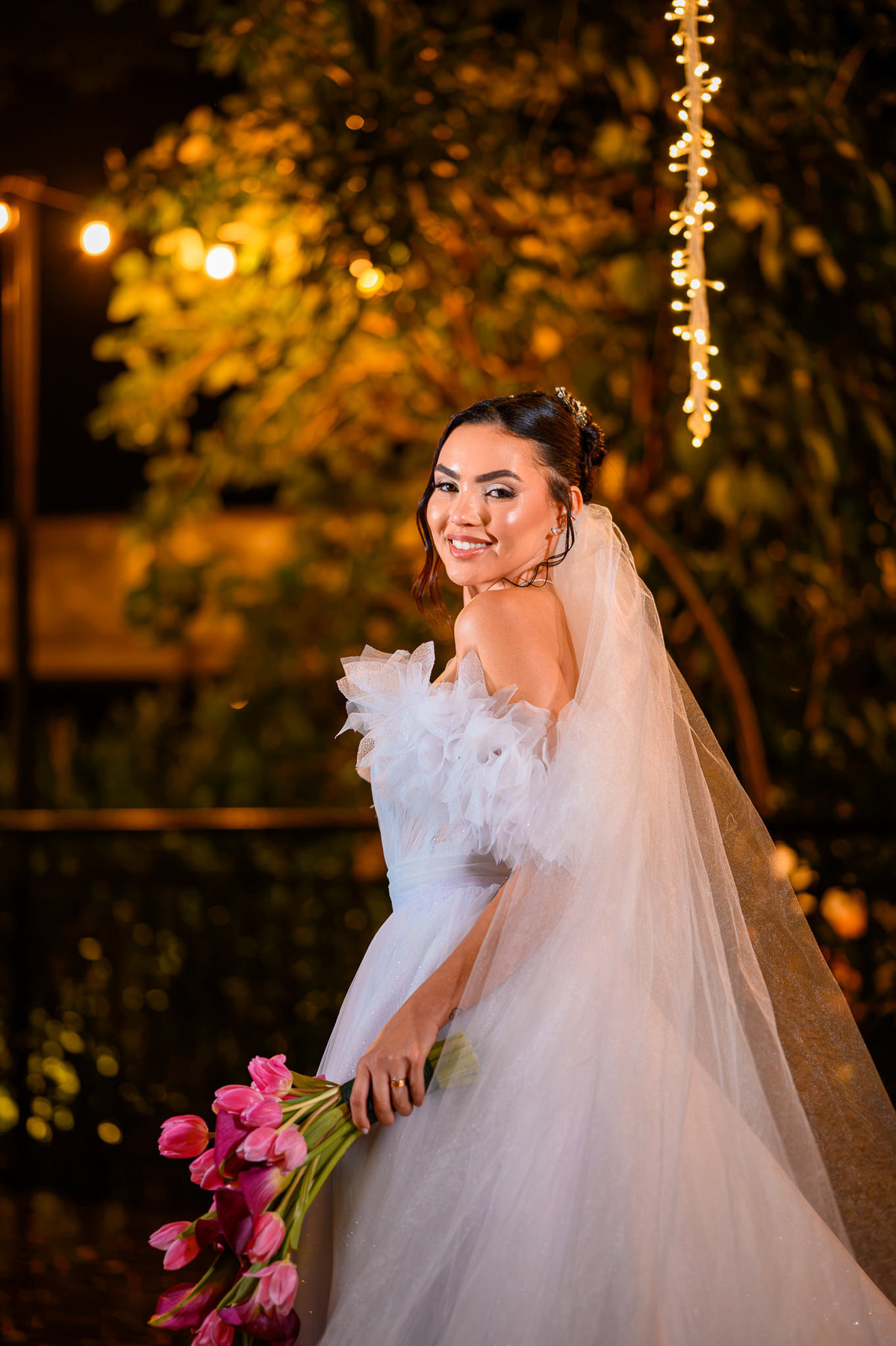 Noiva com vestido e véu sob luzes no Indaiá Eventos