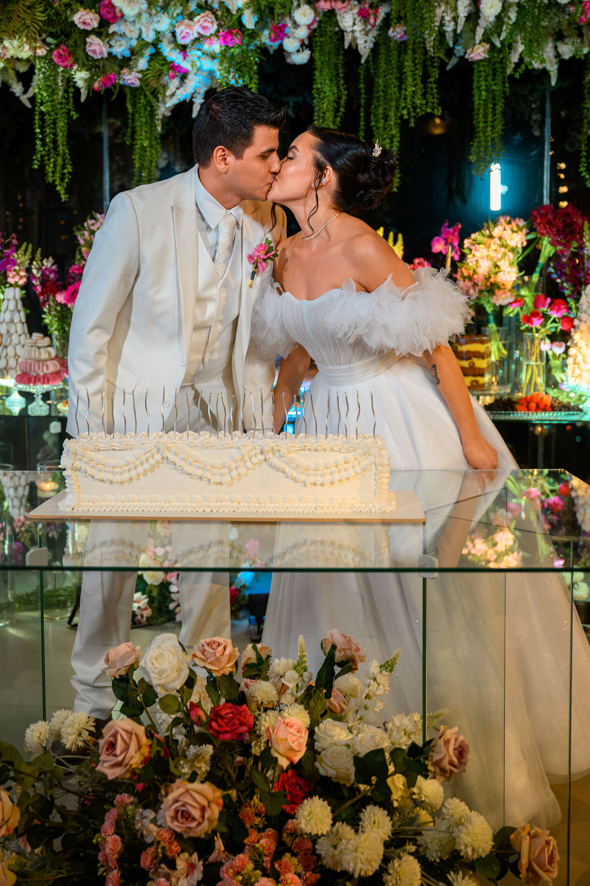 Noiva e noivo beijando diante do bolo de casamento