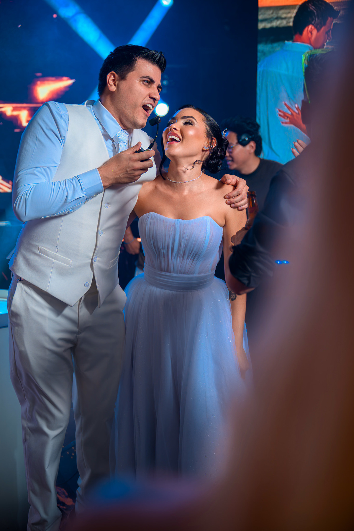 Noiva e noivo cantando e sorrindo durante a festa