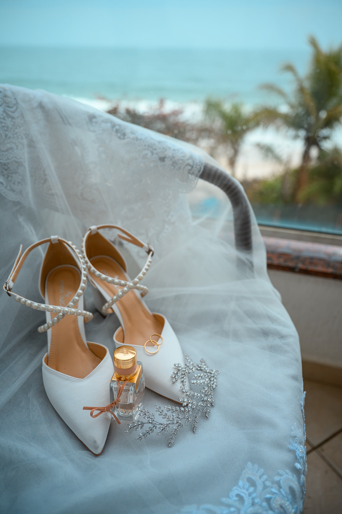 Sapatos, perfume e acessórios da noiva com vista para o mar
