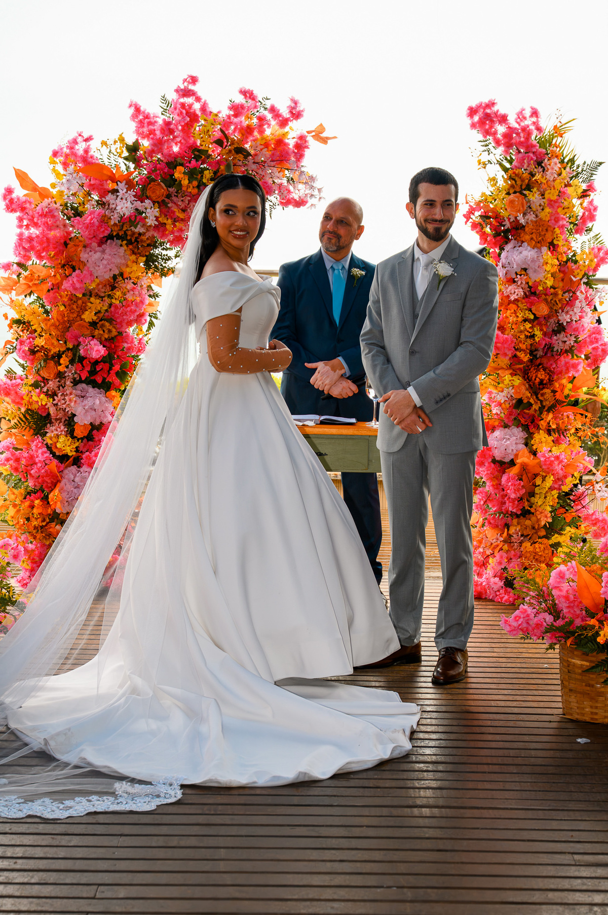 Noivos sorrindo entre flores durante a cerimônia de casamento