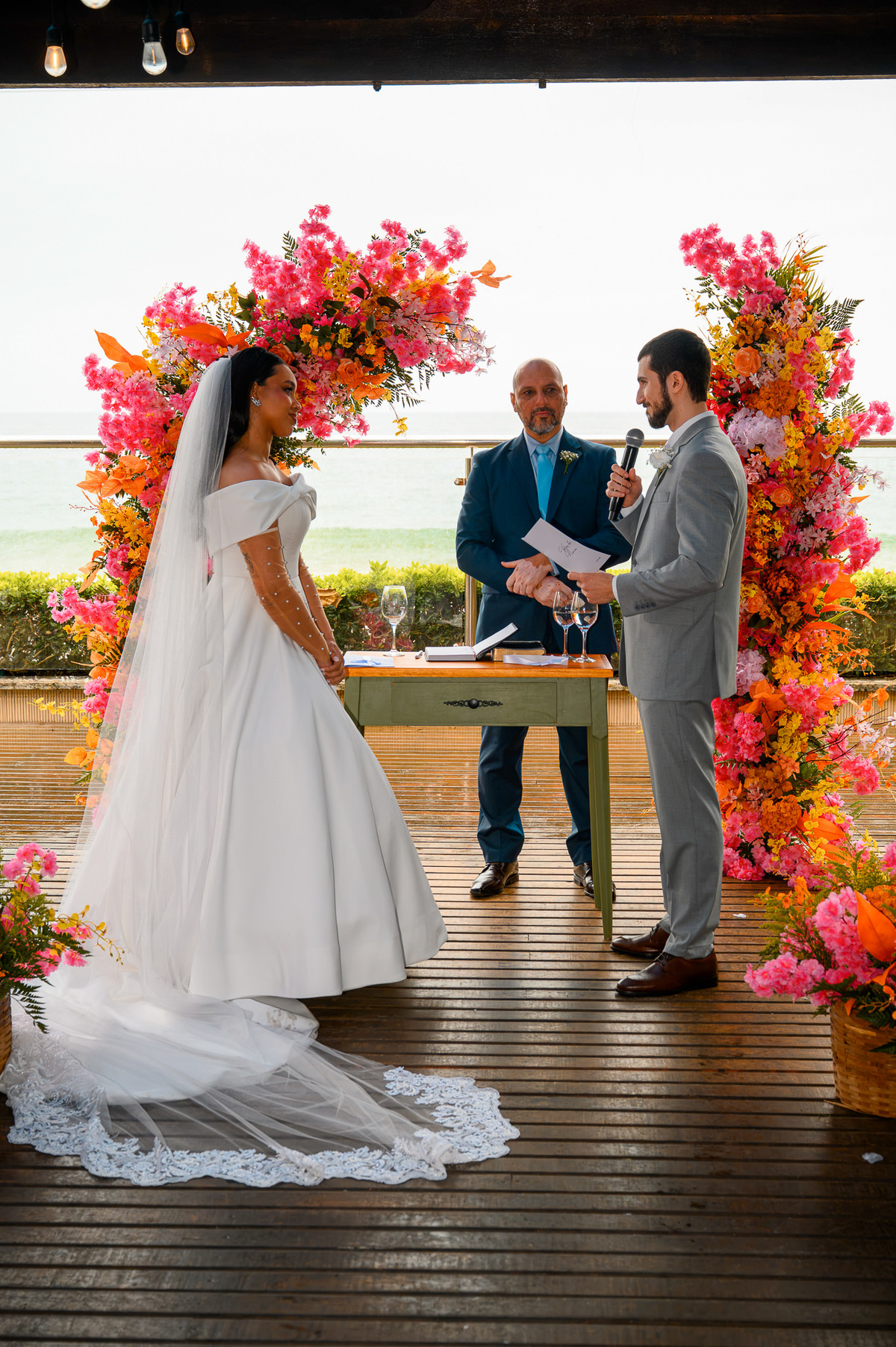  Casal sorrindo na cerimônia com decoração floral vibrante