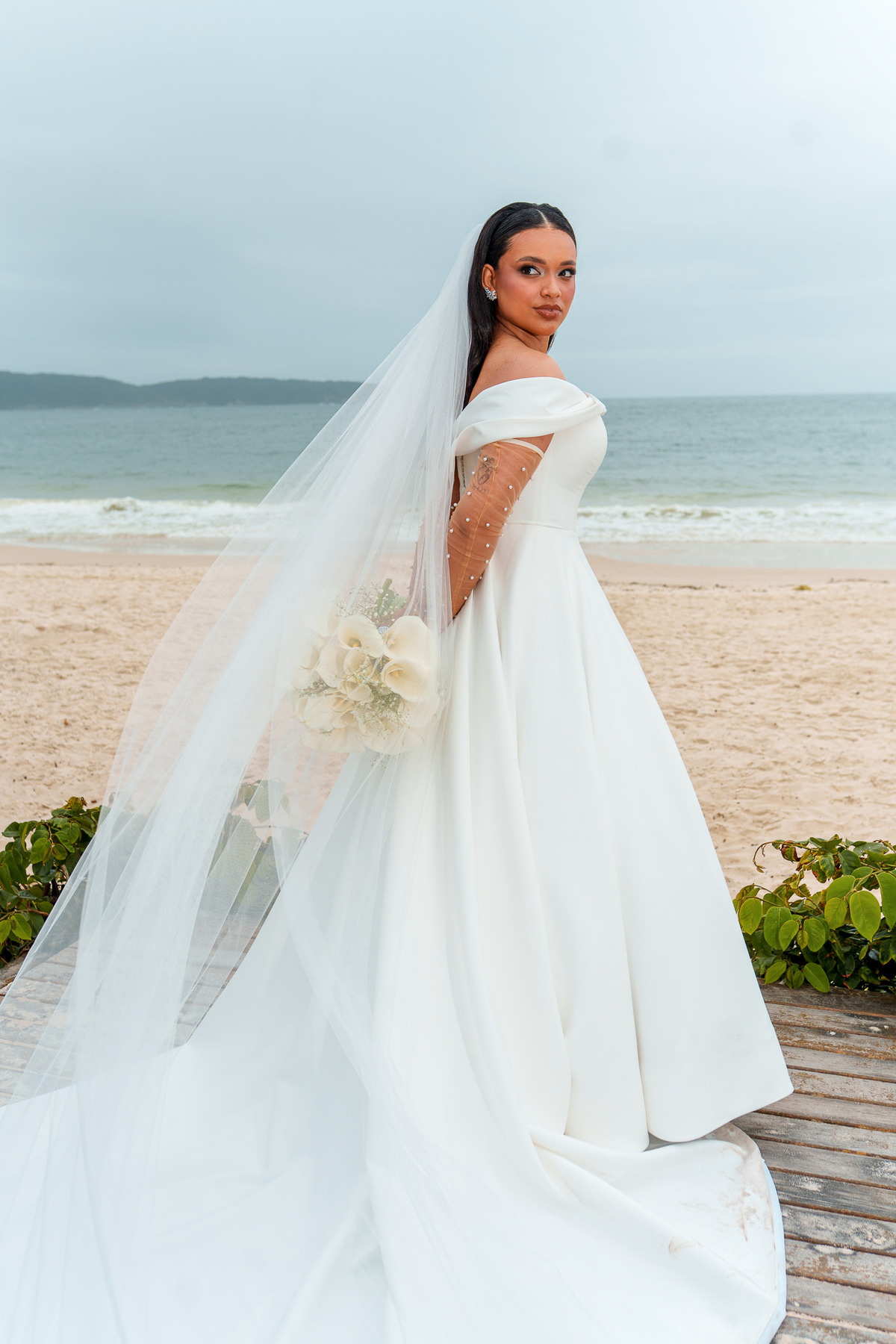 Noiva com buquê branco e o mar ao fundo