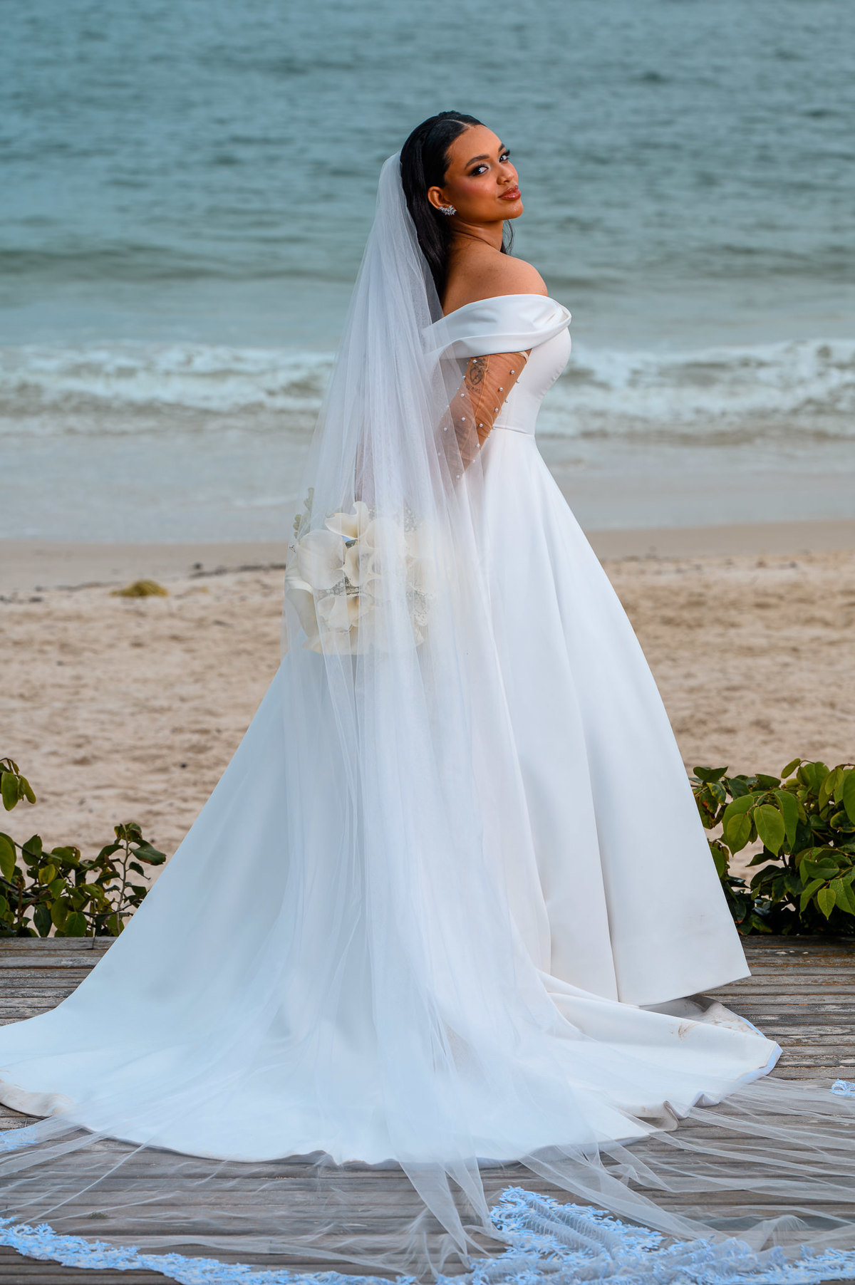 Noiva posando com vestido elegante diante da praia
